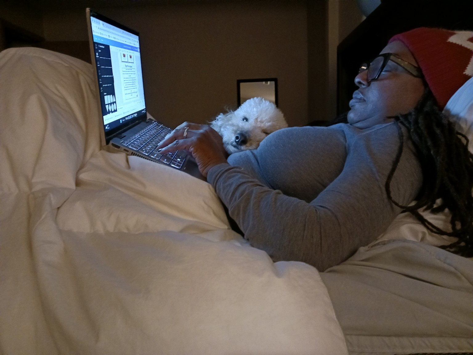Tiffany relaxing with her laptop and a small white dog