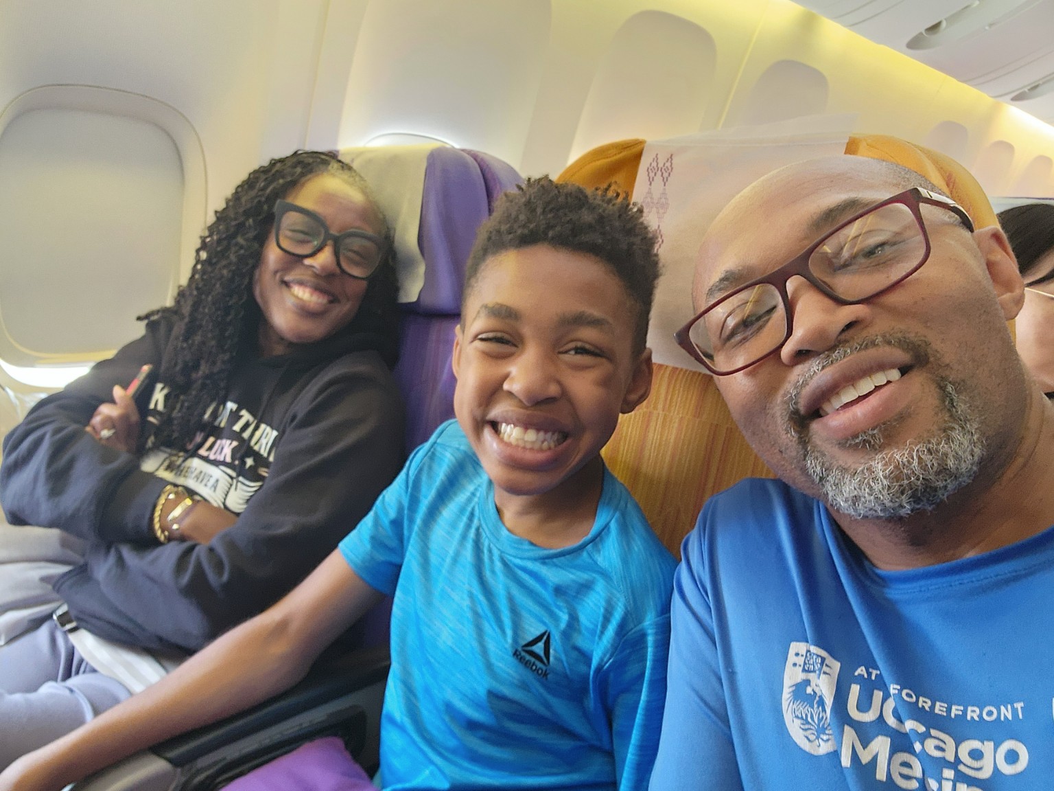 Tiffany, Wendell, and Myles smiling together on a family flight